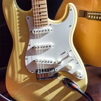 A gold electric guitar against an amplifier